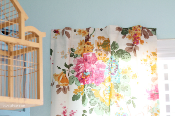 floral curtain hung on wall with upholstery tacks