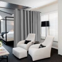 silver grey blackout curtains are being used as a seperator in a bedroom with the bed on one side of the room and the window on the other