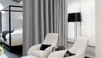 silver grey blackout curtains are being used as a seperator in a bedroom with the bed on one side of the room and the window on the other